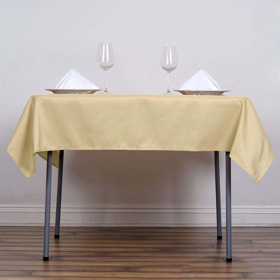 Elegant yellow tablecloth with dinnerware and wine glasses set for a formal dining experience.