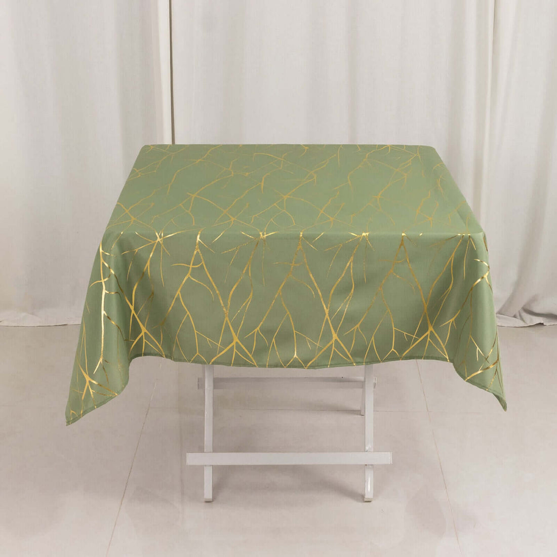 Green tablecloth with gold abstract design on a white table.