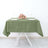 Green tablecloth with plates and floral centerpiece on a table.