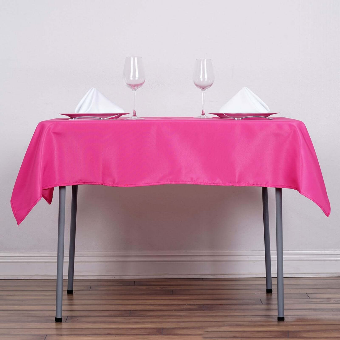 Pink tablecloth draped over a table set with glasses and napkins.
