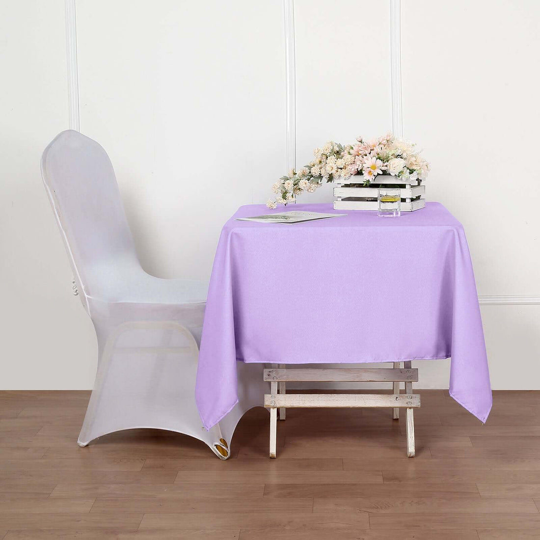 Purple tablecloth draped over a table with a floral centerpiece.