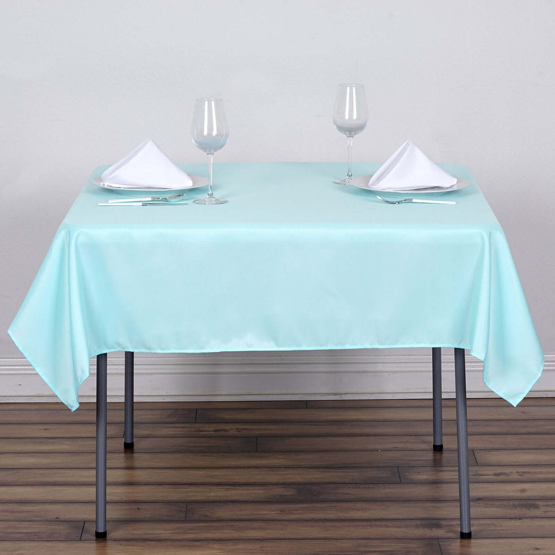 Mint green tablecloth draped over a table set with glasses and napkins.