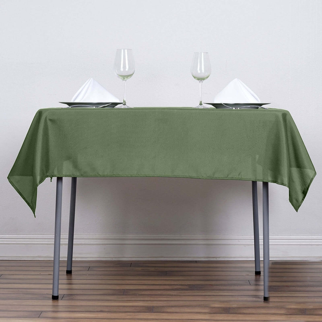 Green tablecloth draped over a table set with plates and glasses.