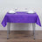Purple tablecloth on a dining table set for two with glasses and napkins.