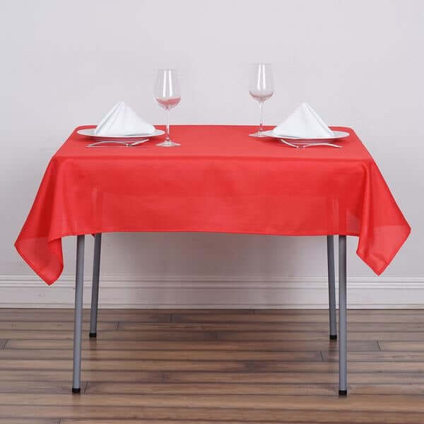 Red tablecloth set on a table with white napkins and glasses.