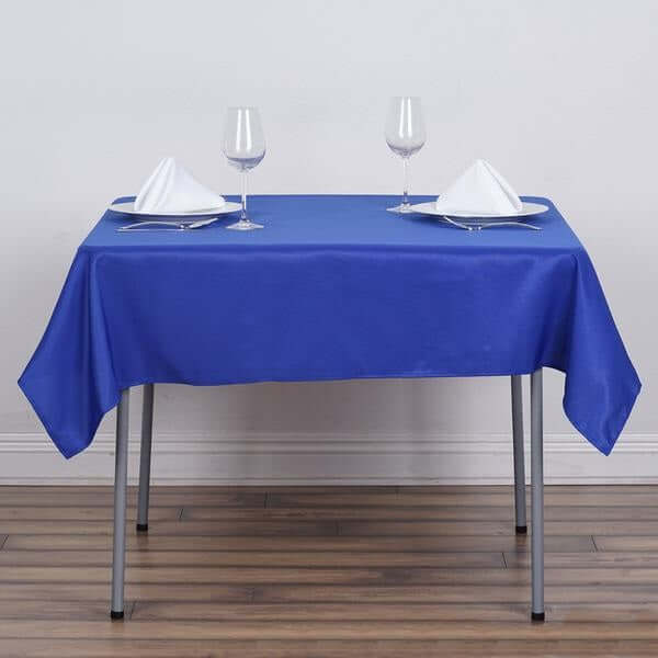 Blue tablecloth set on a dining table with glasses and napkins.