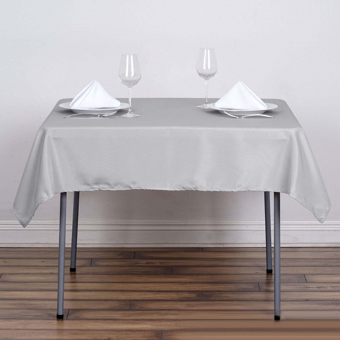 Gray tablecloth set with glasses and napkins on a wooden floor.