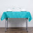 Turquoise tablecloth on a dining table set with plates and glasses.