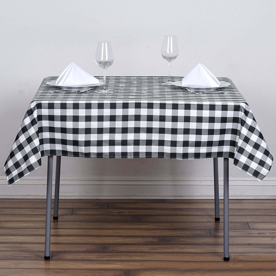 Black and white checkered tablecloth on a dining table with glasses and napkins.