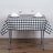 Black and white checkered tablecloth on a dining table with glasses and napkins.