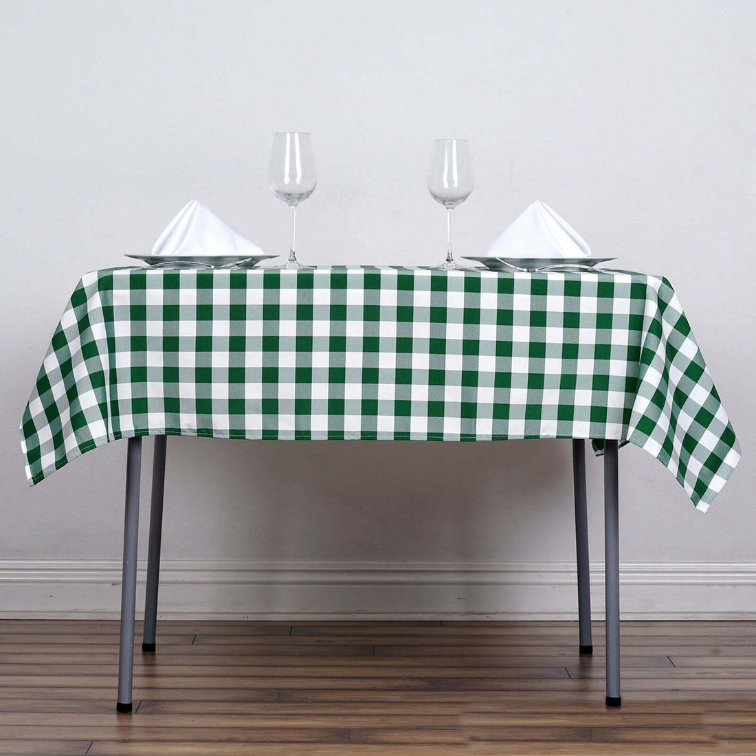 Green and white checkered tablecloth with plates and glasses on a dining table.