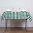 Green and white checkered tablecloth with plates and glasses on a dining table.