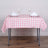 Pink gingham tablecloth on a dining table with glasses and napkins.