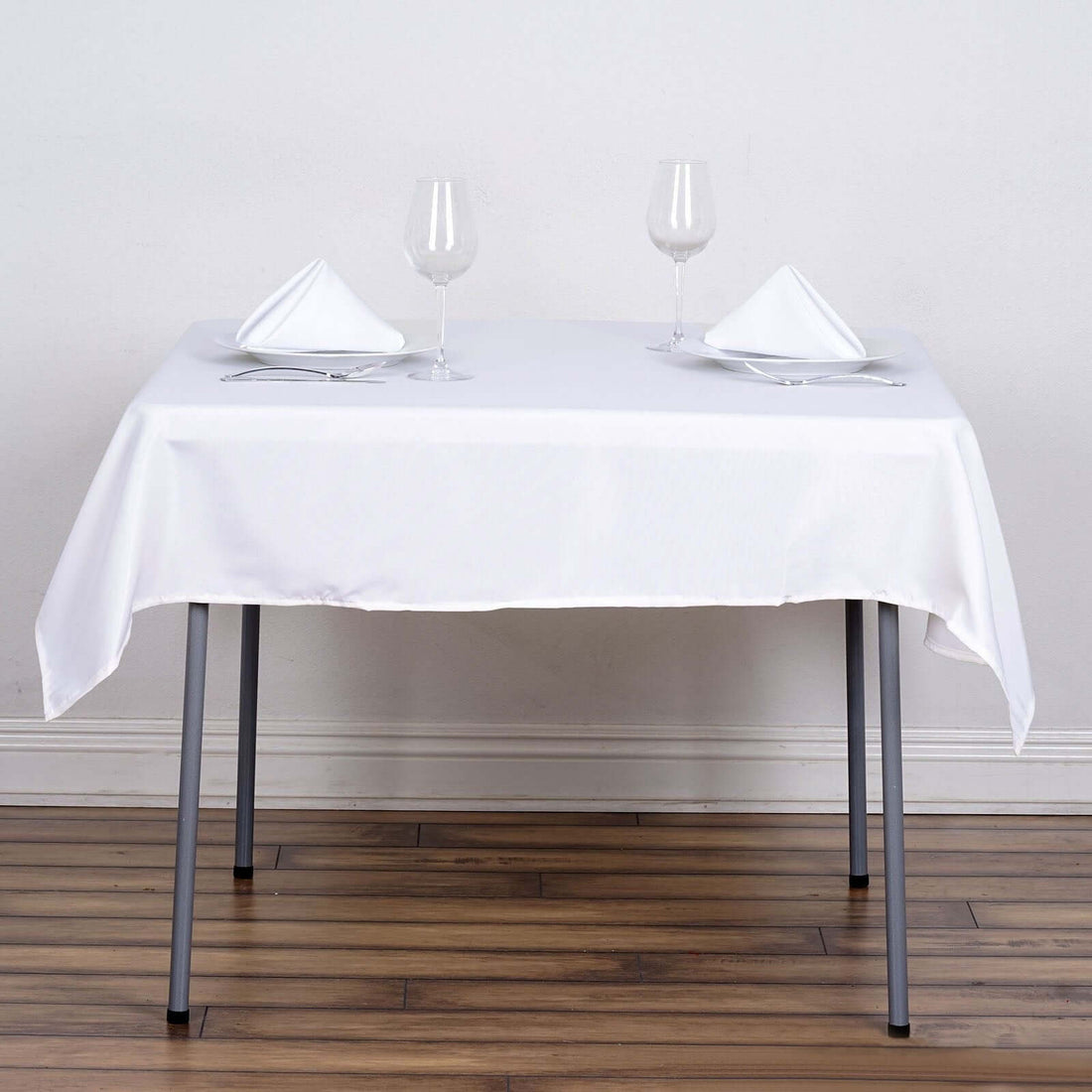 Dining table set with white tablecloth and elegant glassware.