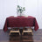 Burgundy tablecloth draped over a wooden table with floral centerpiece.