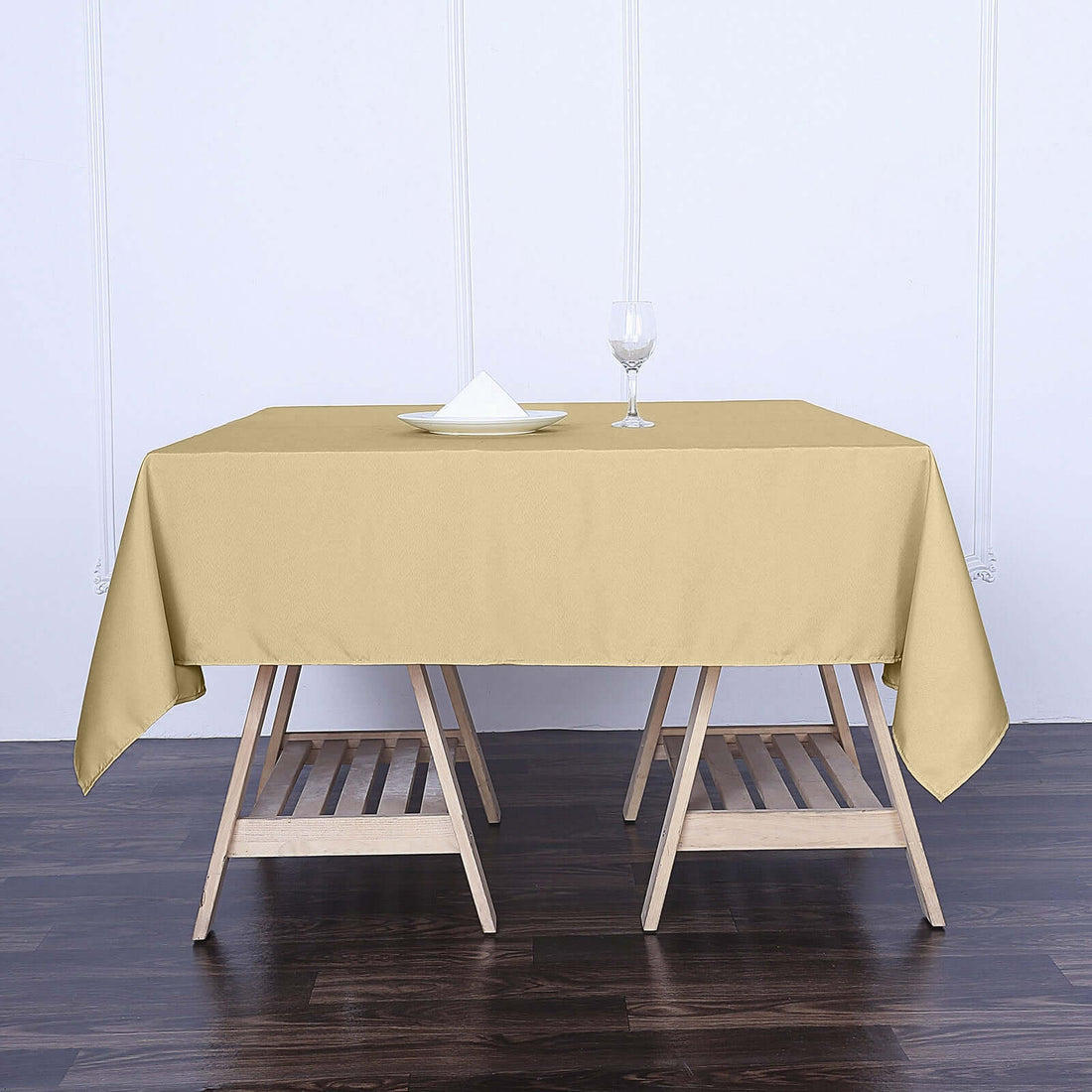 Elegant beige tablecloth draped over a wooden table with a glass and napkin.