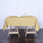 Elegant beige tablecloth draped over a wooden table with a glass and napkin.
