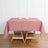 Pink tablecloth on a wooden table with candles