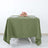 Olive green tablecloth draped over a table with plates and a floral centerpiece.