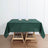 Green tablecloth draped over a wooden table with candle holders on top.