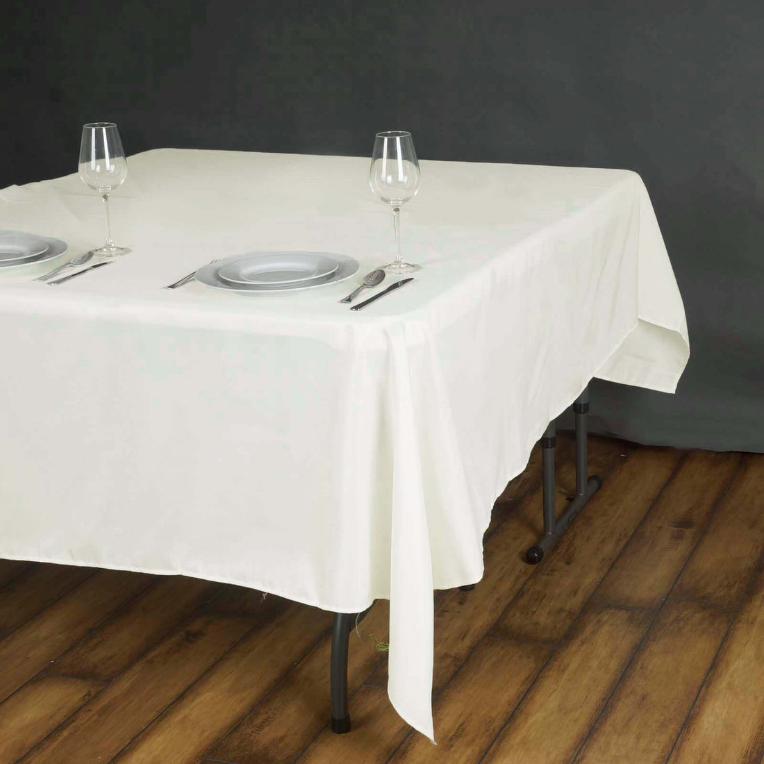White tablecloth draped over a table set with plates and wine glasses.