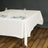 White tablecloth draped over a table set with plates and wine glasses.