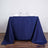Navy tablecloth draped over a table set for two with glasses and napkins.