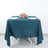Teal dining tablecloth with white plates and pink roses on a plain background.