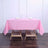 Pink tablecloth on a wooden table set with glasses and napkins.