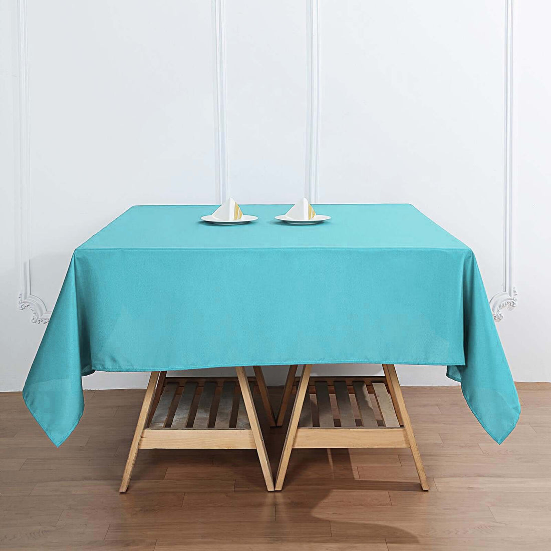 Turquoise tablecloth on a wooden table with two decorative plates.