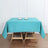 Turquoise tablecloth on a wooden table with two decorative plates.