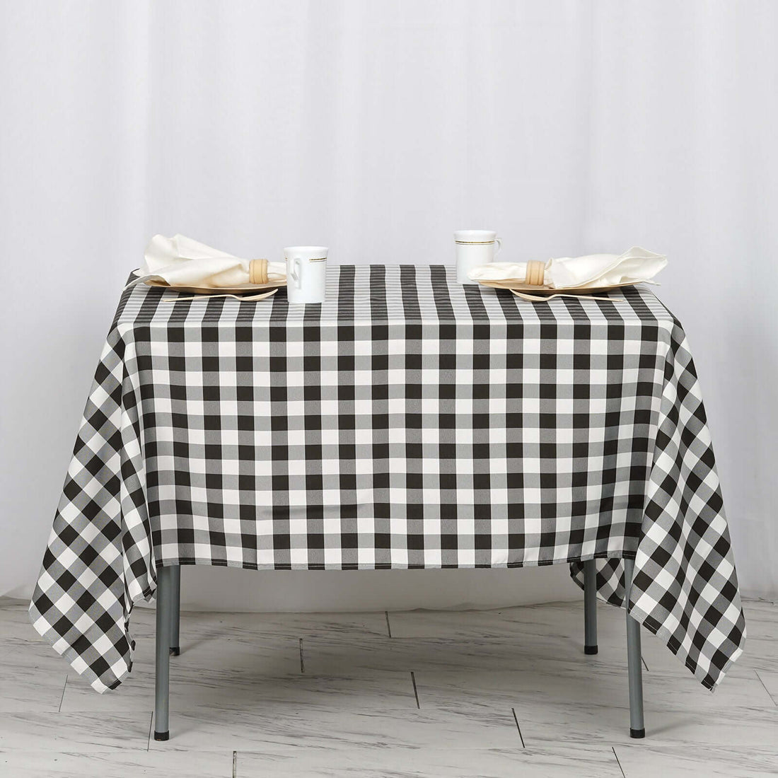 Black and white checkered tablecloth draped over a table with utensils and cups.