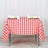 Red and white checkered tablecloth on a table with cups and napkins.