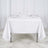 White tablecloth draped over a table set for two with glasses and plates.