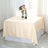 Cream tablecloth draped over a table with a vase of flowers and a wine bottle.