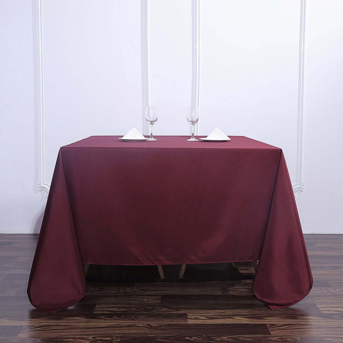 Burgundy tablecloth draped over a table set with glasses and napkins.