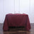 Burgundy tablecloth draped over a table set with glasses and napkins.