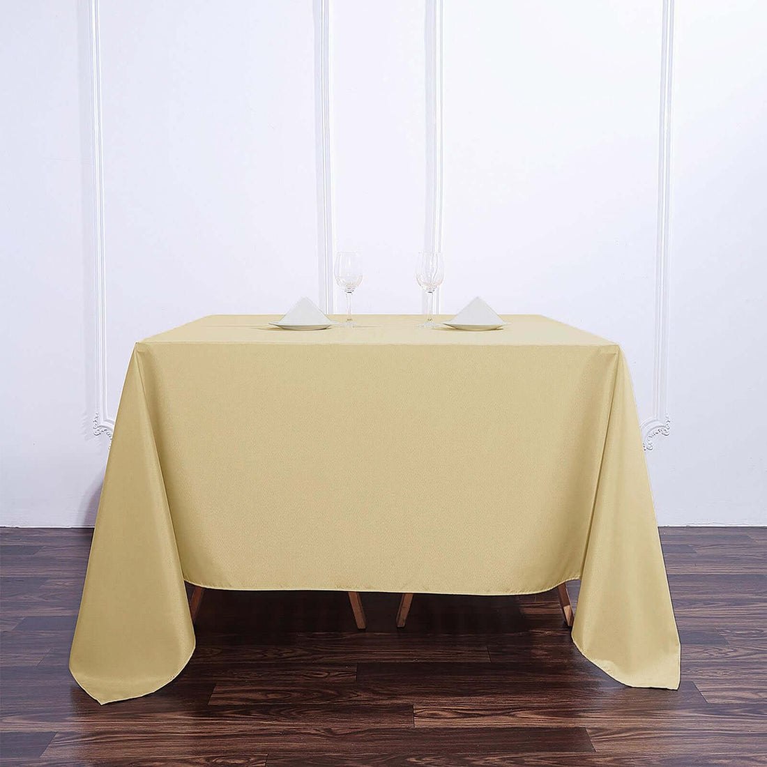 Yellow tablecloth on a wooden table with wine glasses and napkins.