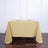 Yellow tablecloth on a wooden table with wine glasses and napkins.
