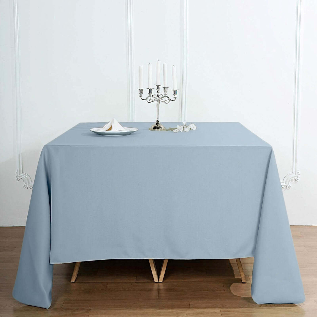 Blue tablecloth draped over a wooden table with a candle holder and decorative items.
