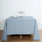 Blue tablecloth draped over a wooden table with a candle holder and decorative items.
