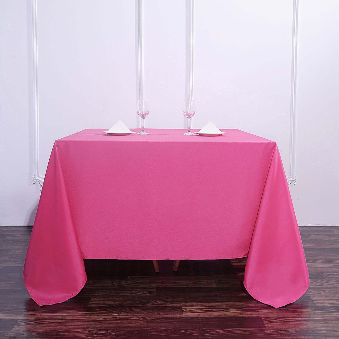 Pink tablecloth draped over a table with candles and glasses