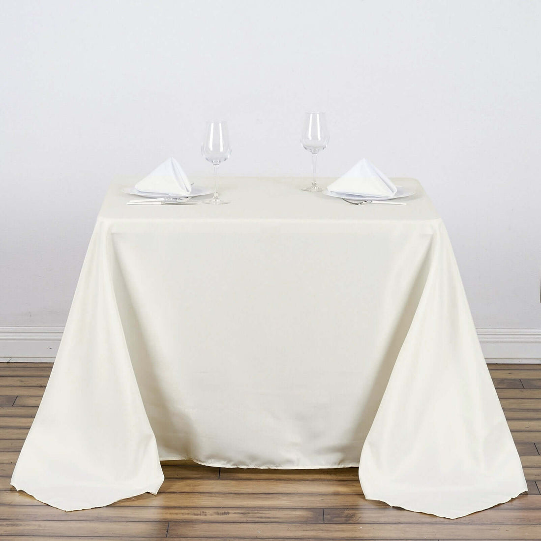 Elegant ivory tablecloth draped over a dining table with napkins and glasses.
