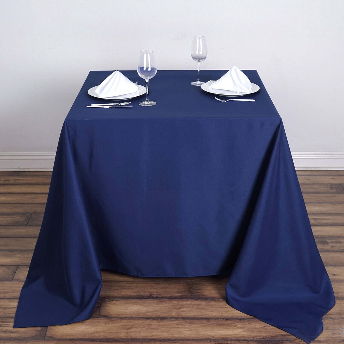 Navy blue tablecloth draped over a table set with plates and glasses.