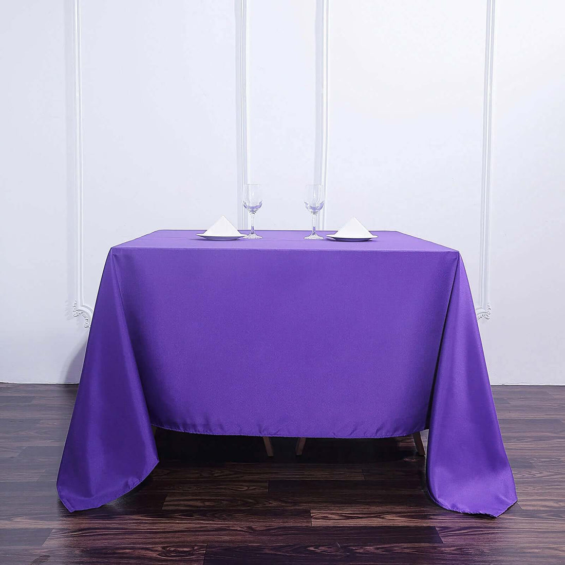 Purple tablecloth draped over a table with wine glasses and napkins