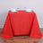 Red tablecloth draped over a table set for two with glasses and napkins.