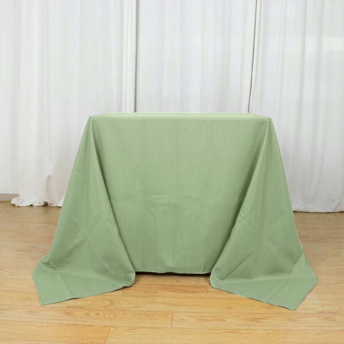 Green tablecloth draped over a table on a wooden floor.