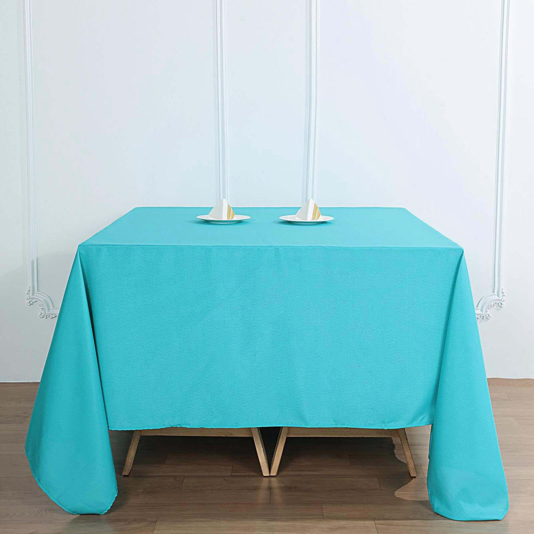 Turquoise tablecloth draped over a wooden table with candle holders