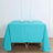 Turquoise tablecloth draped over a wooden table with candle holders