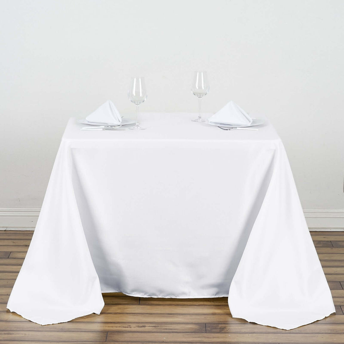 Elegant white dining table setup with glasses and napkins.